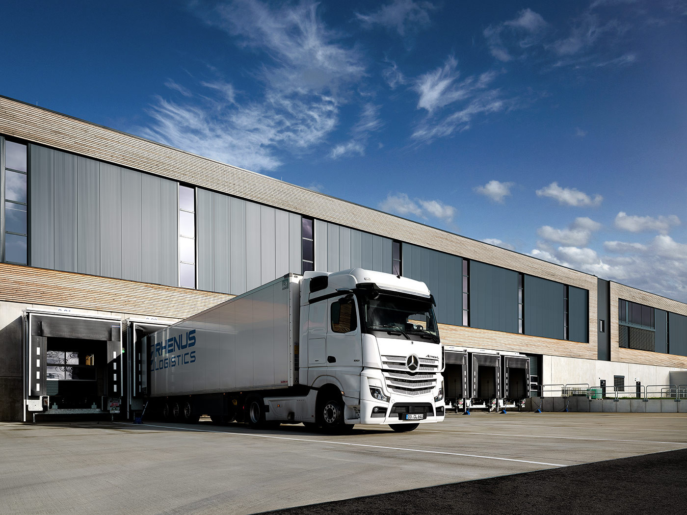 LKW beim entladen vor einem Logistikzentrum, blauer Himmel.